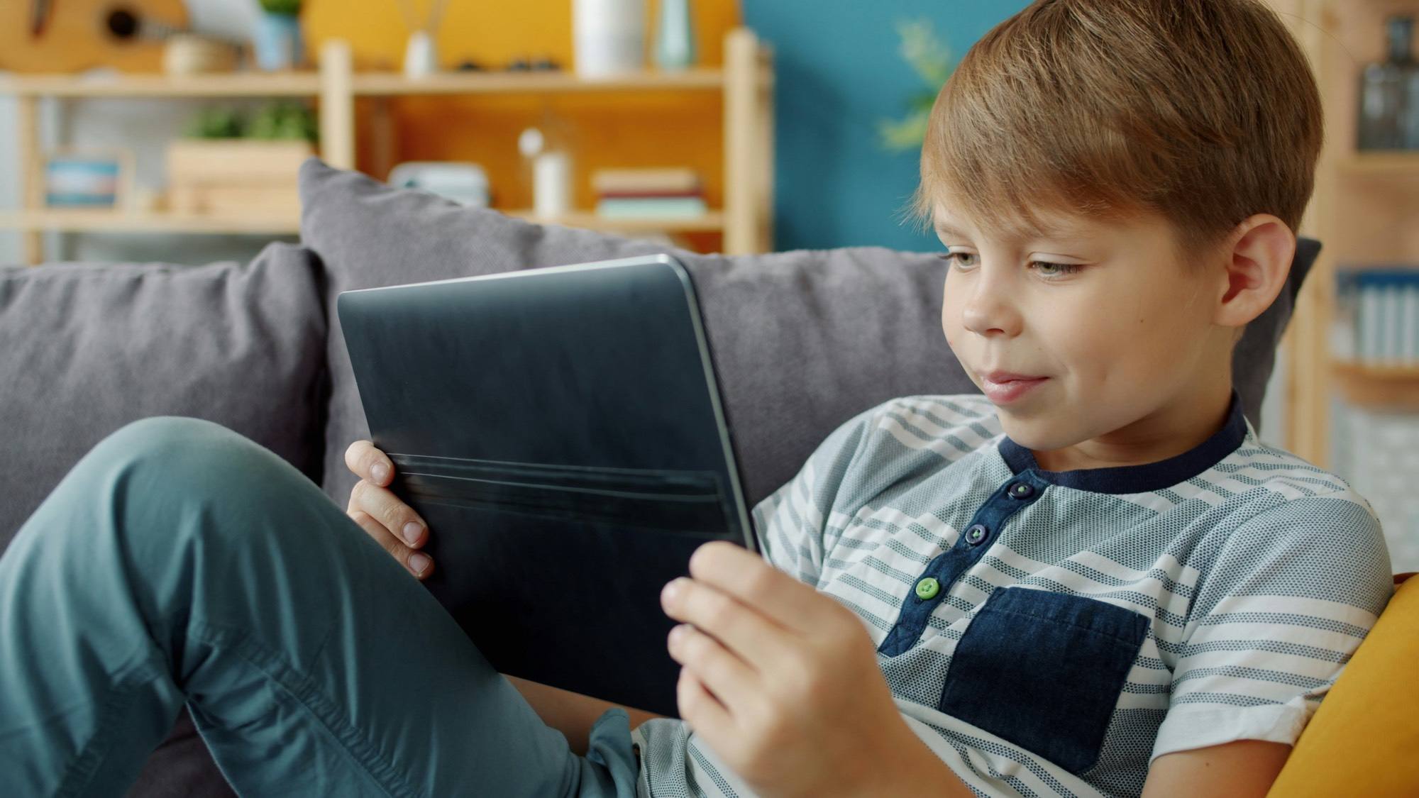 Young boy using a tablet on a couch